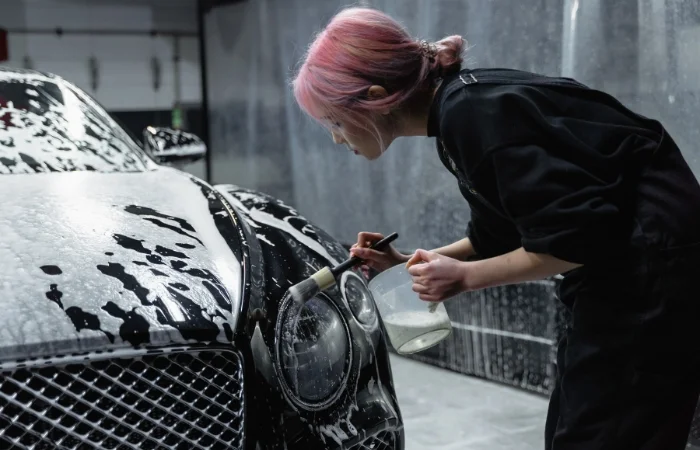 Una ragazza pulisce i fari della propria auto con dei prodotti specifici